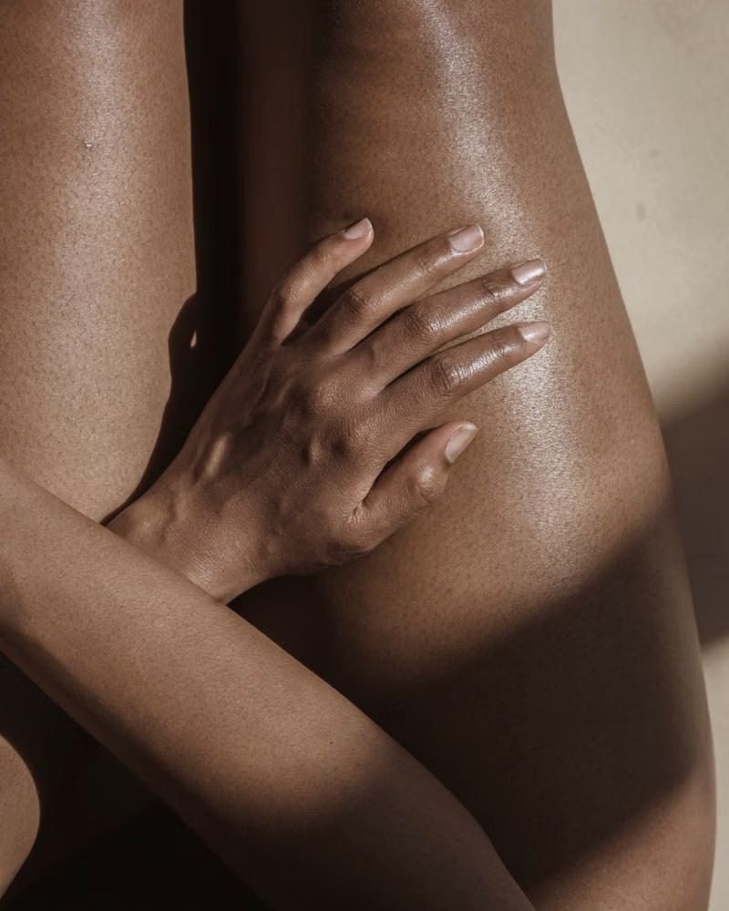A hand resting on smooth, glowing skin in warm light