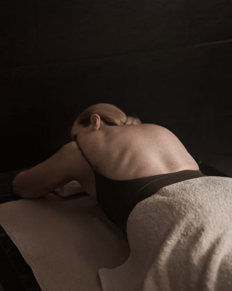 A client resting face down on a massage table in a softly lit room